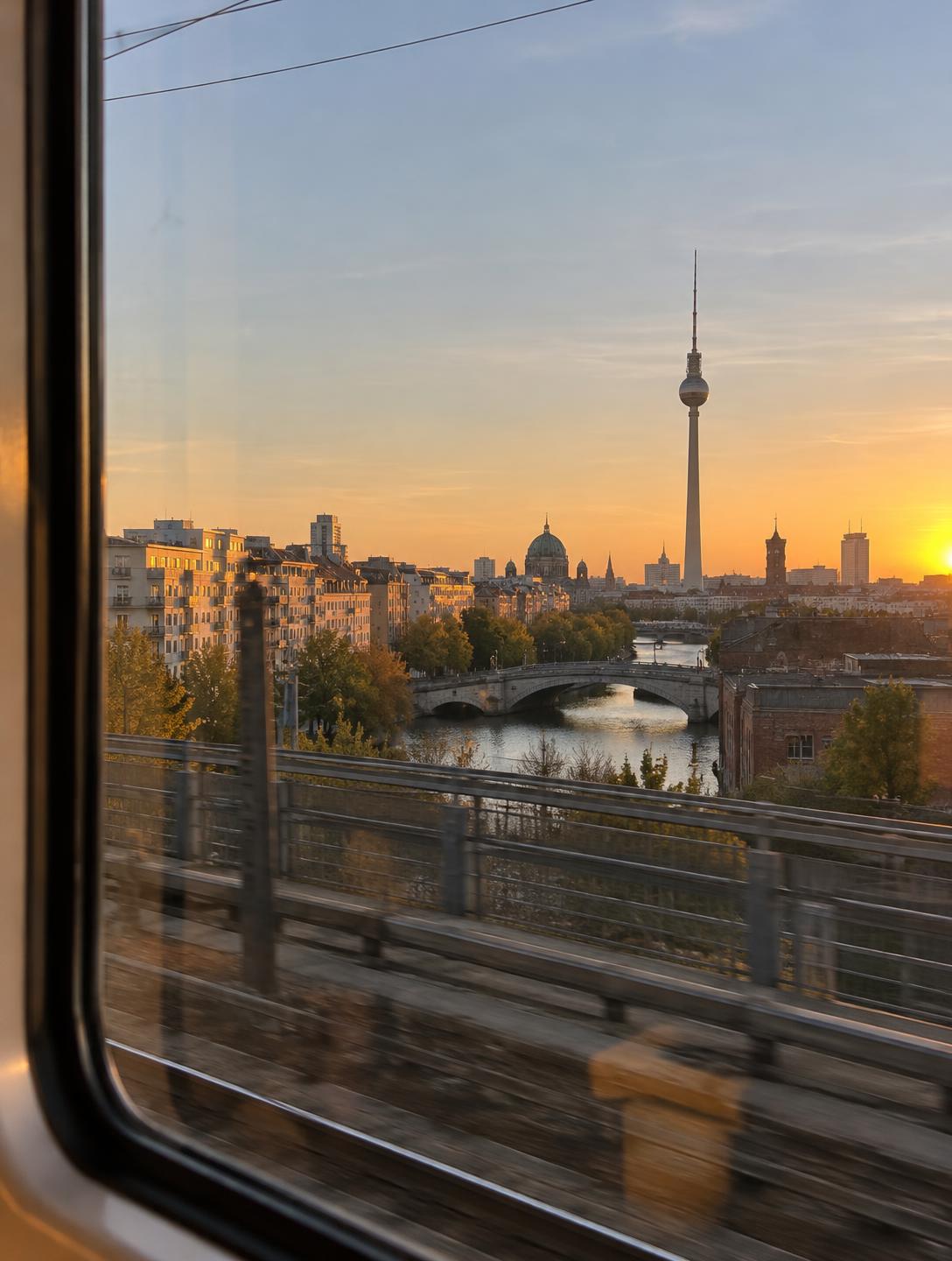 Golden-hour view over Berlin seen from the window of a moving train